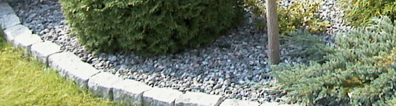 Granitskærver anvendt som bunddække i havebed med chaussesten som kant.